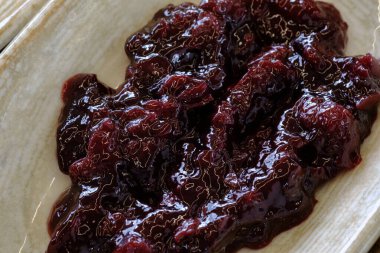 Yakın plan koyu renkli meyveler muhtemelen kiraz ya da eriği sığ bir tabakta zengin ve çökmüş olarak saklar.