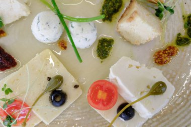 Rafine bir mutfak deneyimi için sanatsal olarak hazırlanmış peynirli otlar ve zeytinlerden oluşan nefis bir düzen.