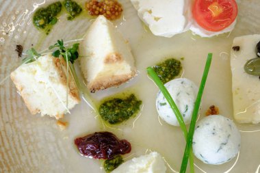 Peynir tabağında çeşitli otlar ve soslar var.