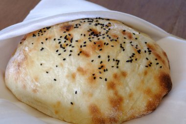 Siyah tohumlarla serpilmiş taze pişmiş bir ekmek beyaz bir peçetenin üzerinde duruyor.
