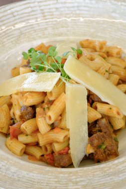 Tıraş edilmiş peynir ve taze otlarla kaplı domates soslu makarna içeren nefis bir makarna.