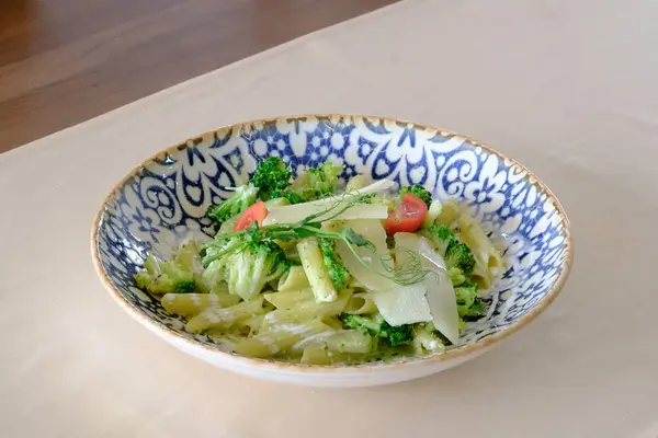 Brokolili kremalı makarna tabağı ve tıraş edilmiş peynirle süslenmiş vişneli domates.