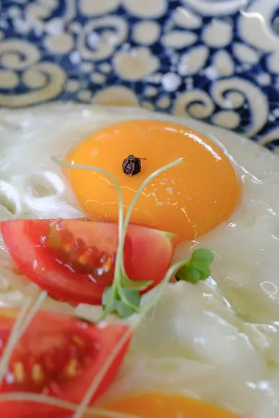 Canlı yumurta sarısı ve taze domates ve bitkilerle süslenmiş mükemmel bir kızarmış yumurta.