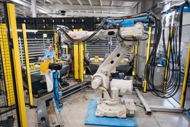 Bir fabrikada robotik kol üreten endüstriyel otomasyon hassas bir üretim olduğunu gösteriyor.