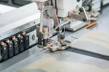 Endüstriyel bir ortamda dikiş makinesinin kumaşı kapama hassasiyeti ve otomasyonu gösteriyor.