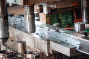 Endüstriyel imalat ortamında hidrolik pistonlarla metal baskı oluşturan parçalar.