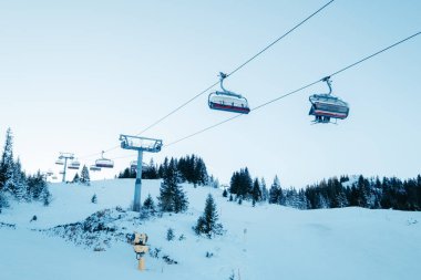 Karlı bir dağda kayak kaldırışı. Evergreen ağaçları mavi gökyüzünün altındaki yamaçlarda kışın harikalar diyarı vaat ediyor.