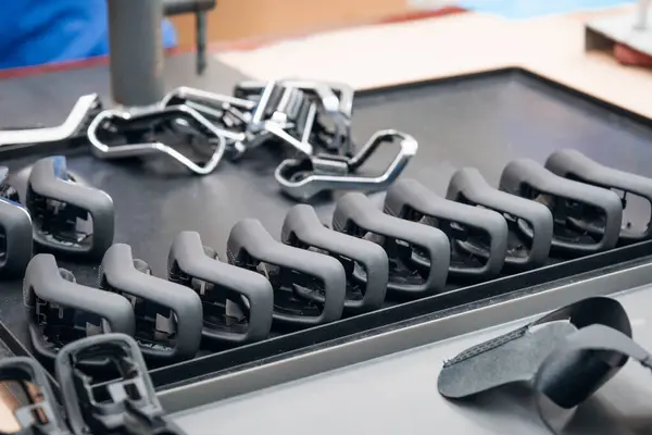 Metalik bir yüzey üzerinde düzenli olarak düzenlenmiş çeşitli aşamalarda bisiklet koltuğu bileşenlerini içeren üretim hattı