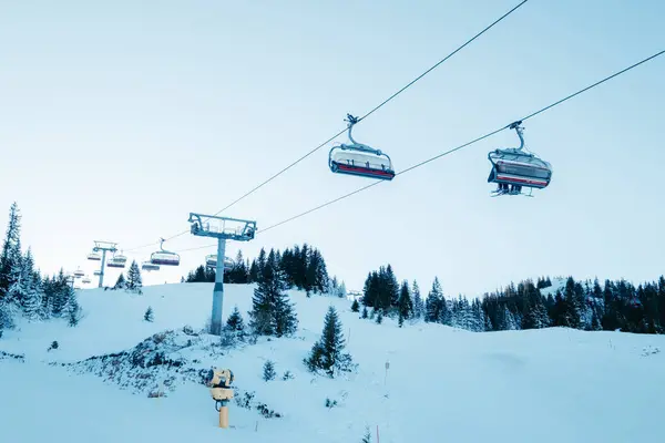 Karlı bir dağda kayak kaldırışı. Evergreen ağaçları mavi gökyüzünün altındaki yamaçlarda kışın harikalar diyarı vaat ediyor.