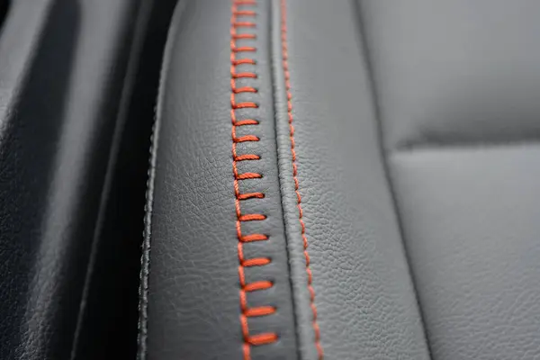 Turuncu dikişli gri deri koltuğu kapat. Detaylı çekim.