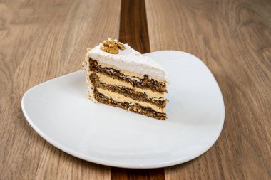 Tabaktaki katmanlı kek tepsisi beyaz kremayla kaplı ve cevizlerle süslenmiş.