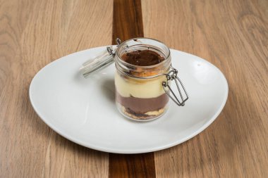 Tatlı kavanozu: beyaz tabakta servis edilen çikolata vanilya ve kurabiye kırıntıları ve ahşap masa