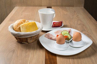 Yumurtalı sandviç, jambon ve sebzeli kahvaltı basit bir sabah yemeği için ahşap bir masada servis edilir.