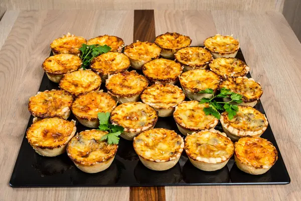 Partiler için mükemmel, parlak, siyah bir tepsiye yerleştirilmiş altın hamurlu turtalar.