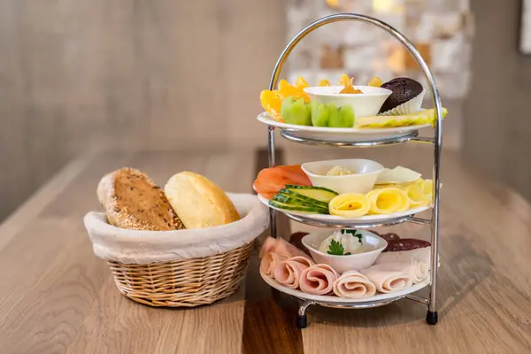 Kahvaltı kulesini süsleyin. Meyveli ekmek, peynir ve ahşap masada servis edilen çörekle.