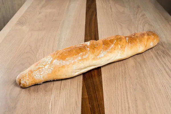 Tarafsız ahşap bir yüzey üzerinde altın kahverengi baget. Mükemmel pişmiş ve eğlenmeye hazır.