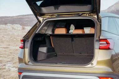 Arka koltukları ve geniş kargo alanını gösteren bronzlaşmış bir arabanın bagajını aç. Hatchback kaldırıldı. Doğal arazide ulaşım.