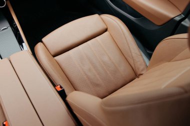 Yakın plan bir vitrin, bronzlaşmış deri bir araba koltuğu, delinmiş detaylar ve tasarımı vurgulanıyor. Koltuğun ergonomik yapısı konfor ve tarzı gösteriyor..