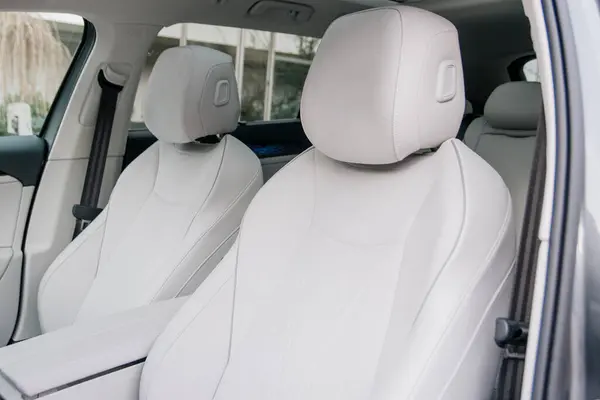 Pürüzsüz başlıkları olan beyaz deri koltuklara yakın plan. Minimalist estetik, aracın lüks ve rahat iç tasarımını ön plana çıkarıyor..