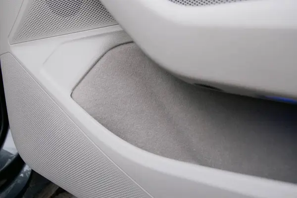 Solunda hoparlör olan bir araç kapısını ve gri keçeli kalemle kaplı açık bir depoyu kapat. Kapı beyaz plastik..