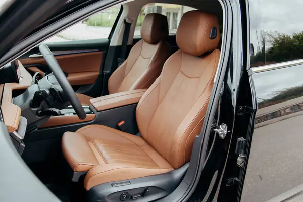 Bronz deri koltuklu lüks bir araç. Direksiyon simidi ve konsol ayrıntıları. Konfor ve üst düzey tasarım.