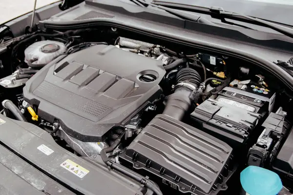 Yakından çekilen görüntü modern bir araba motoruna odaklanıyor. Detaylar arasında motor bloğu, hava girişi ve yardımcı bileşenler yer alıyor. Araç bakım sahnesi.
