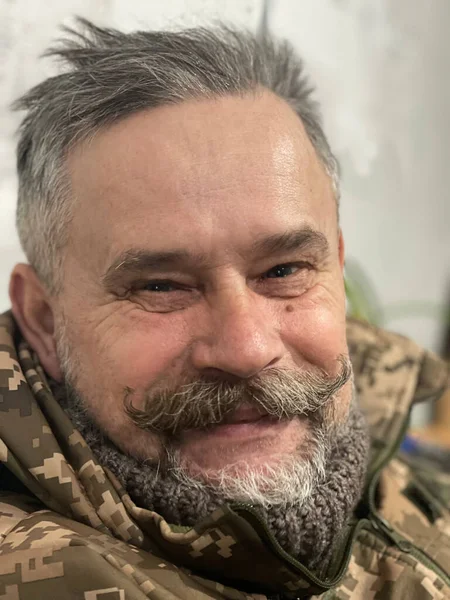 Satisfied face of a smiling elderly Ukrainian soldier with mustache and beard