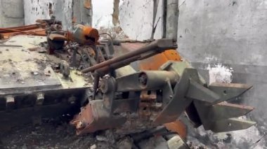 Savaş sırasında Ukrayna 'da topçu mermileriyle yıkılan evde, tankın paslı ve kırık tarafı ve parçalanmış piyade savaş aracı duruyor.