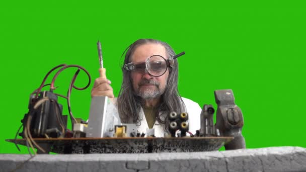 狂ったコンピュータ修理工は ハンマーとハンダ付け鉄でマザーボードを修復し 煙ではんだ付けし ように表示します 長髪で額に虫眼鏡と懐中電灯を持つ高齢者 — ストック動画