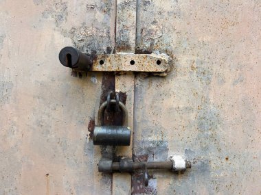 Eski garaj kapısı üç kilitli, eski püskü demir kapı.