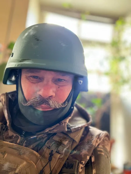 Bıyıklı ve koruyucu kasklı yaşlı bir asker Ukrayna 'daki savaş sırasında askeri üniformasını kamufle ediyor.