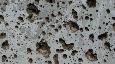 Ev duvarı mermi ve bomba şarapnel parçalarıyla delik deşik edilmiş.