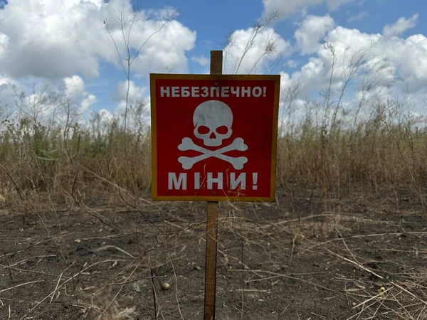 乌克兰战争期间在农田附近的乌克兰语危险信号地雷 翻译为 地雷危险 图库照片