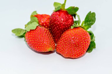 Beyaz arka planda yaprakları olan çilekler..