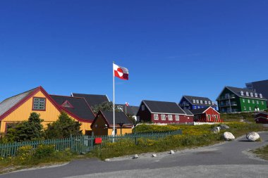 Nuuk 'ta Grönland bayrağı mavi gökyüzünün altında dalgalanan evler.