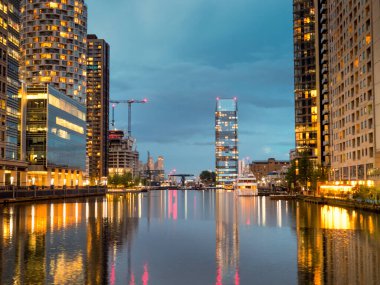 Yüksek binaların ışıkları Londra 'daki Canary Wharf' taki Thames Nehri 'ni yansıtıyor..