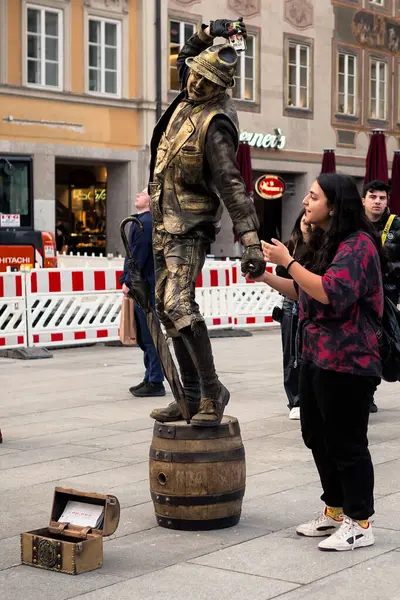 stock image A man performing as a living statue is grabbing a phone of a spectator and is threatening to smash it on the ground.