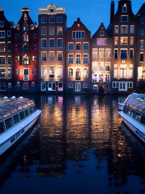 Kanalın üzerine alacakaranlık düşerken, tarihi cephelerden gelen sıcak ışıklar durgun suyun üzerinde parıldıyor. Sahne, mimari, su ve şehir hayatının sessiz ritmi arasındaki ebedi uyumu yakalar..