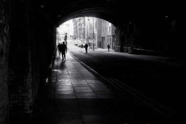 Bir grup insan Manchester, İngiltere 'deki eski bir köprünün altındaki tünelde yürüyor..