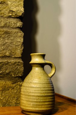 Şöminenin köşesindeki tek bir kil vazonun iç duvardaki gölgelere karşı yakın çekim görüntüsü..