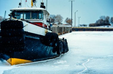 Limandaki donmuş suda römorkör Mavi, berrak bir gökyüzünün altında iskelenin yanında..
