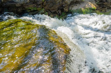Büyük bir kaya çıkıntısının üzerinden akan suyun yakın çekimi köpüklü su oluşturur..