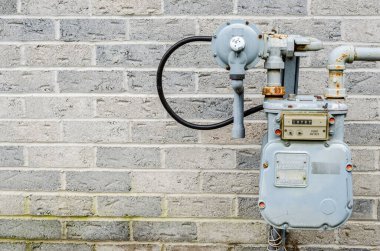 Gri tuğla duvarın yanındaki doğal gaz sayacına yakın plan.