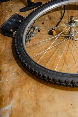 Tahta tezgahta tamir aletleri ve kesesi olan bisiklet tekerleği ve lastik.