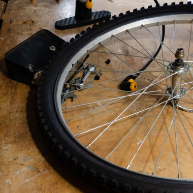 Tahta tezgahta tamir aletleri ve kesesi olan bisiklet tekerleği ve lastik.