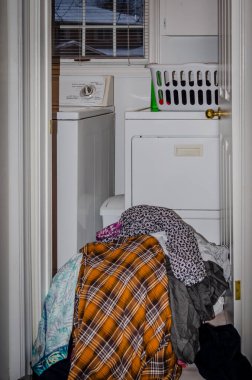 Kışın çamaşır makinesinin önünde kirli çamaşırların sepete dökülmesi.