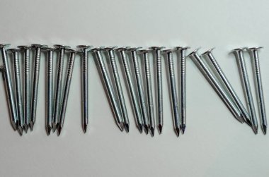 Beyaz arka planda yatay sırada gümüş çatılı çiviler.