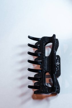 Geniş siyah desenli, gölgeli bir yay saç tokasının yakın çekimi, arka plandaki dişleri vurguluyor.