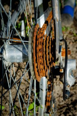 Güneşte terk edilmiş bir biysikletin paslı arka dişlisinin yakın çekimi.