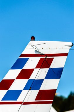 Mavi gökyüzüne karşı küçük uçak kırmızı, beyaz ve mavi kuyruk yüzgeci